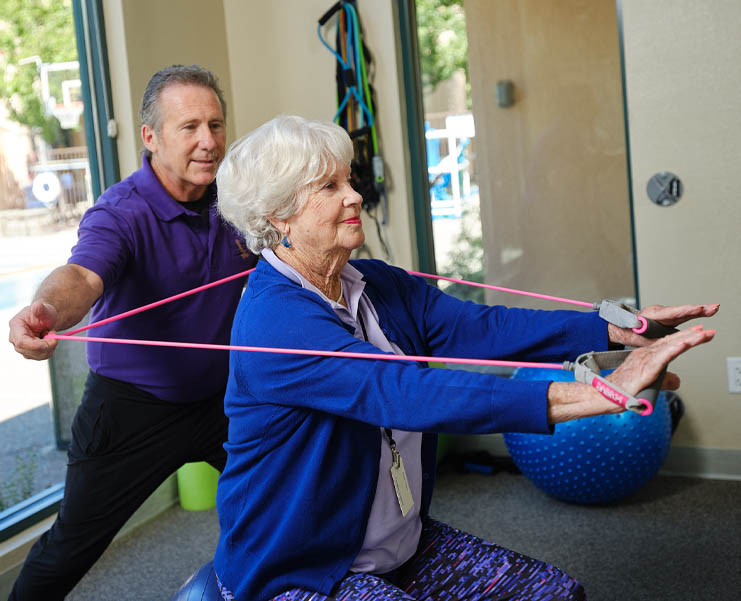 A woman uses resistance bands while working with a physical therapist