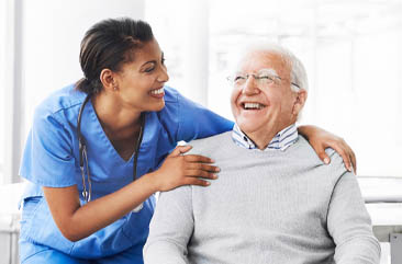 A health care worker holds the shoulders of a seated man