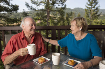A senior couple eat breakfast outside on their patio