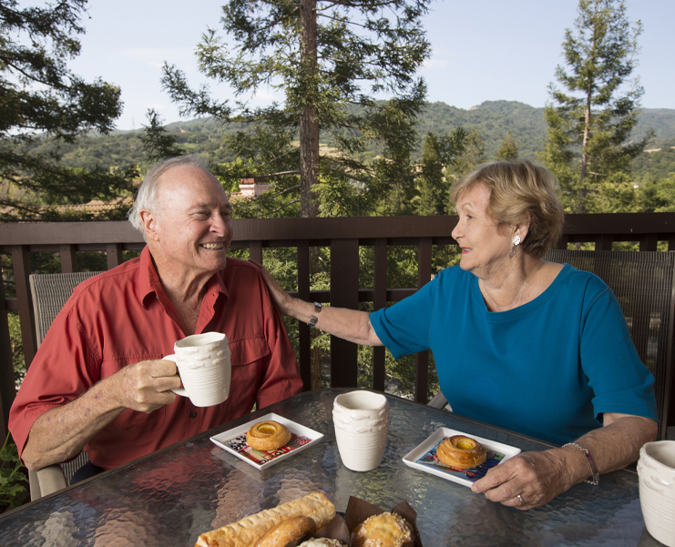 A senior couple eat breakfast outside on their patio