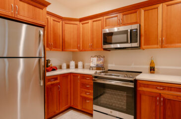 A kitchenette with wood cabinets and chrome appliances
