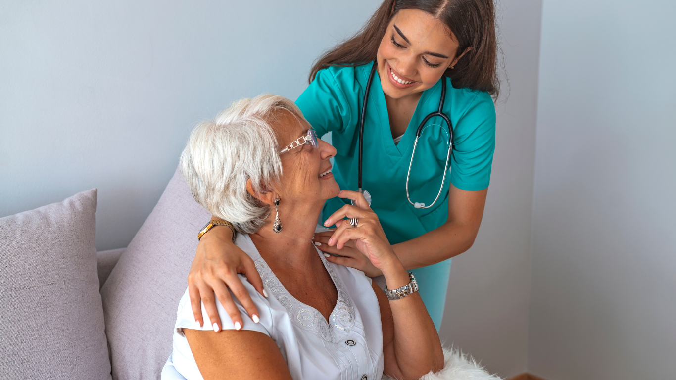 A health care worker places her arm around a senior woman